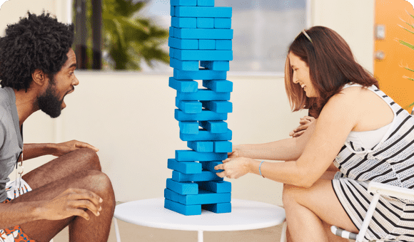 Two people playing a wood tumbling tower game