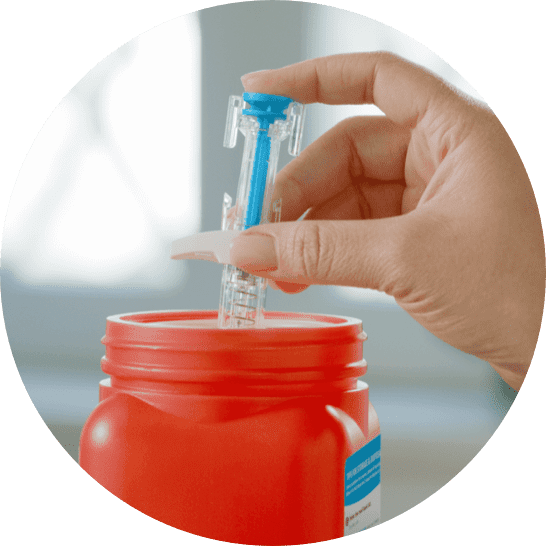 A skyrizi syringe being disposed of in a sharps container